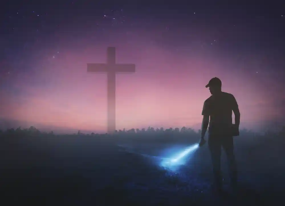 man seeking for God's blessings at the cross with a flashlight